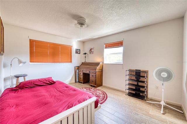 bedroom featuring ceiling fan, a textured ceiling, and light wood-type flooring