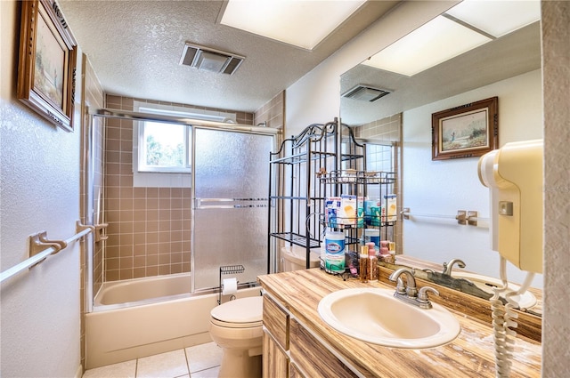 full bathroom with bath / shower combo with glass door, vanity, toilet, tile patterned floors, and a textured ceiling