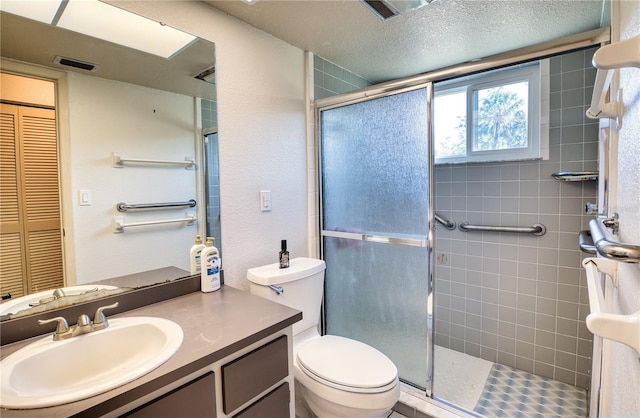 bathroom with vanity, toilet, an enclosed shower, and a textured ceiling