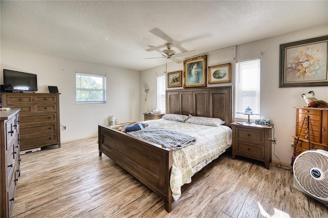 bedroom with multiple windows, ceiling fan, light hardwood / wood-style floors, and a textured ceiling