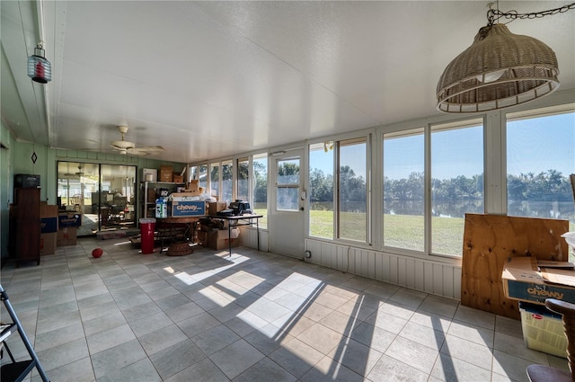 sunroom featuring ceiling fan and a water view