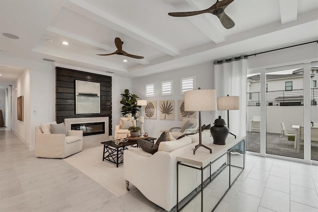 living room with ceiling fan, a large fireplace, and beam ceiling