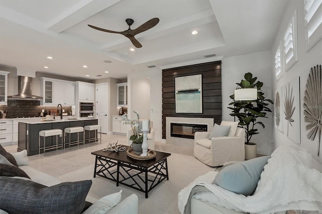 living room with ceiling fan, a large fireplace, and sink