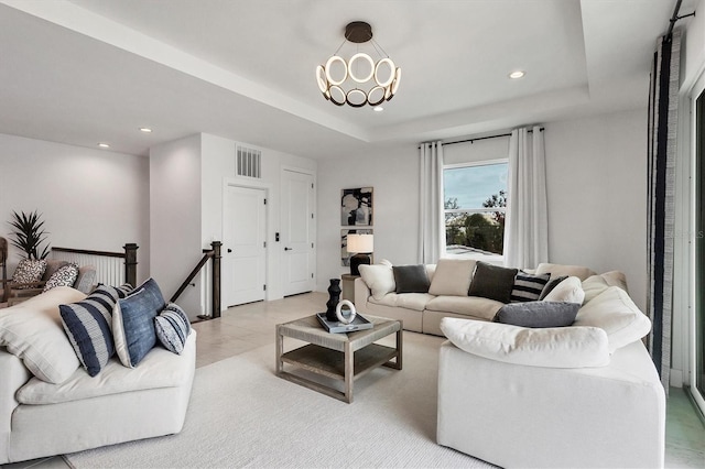 living room with a tray ceiling and a chandelier