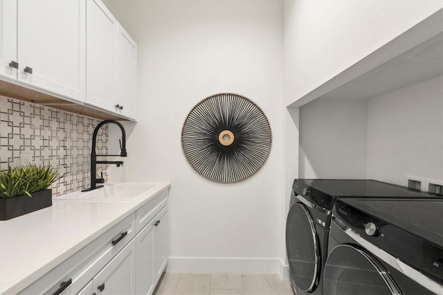 laundry area featuring cabinets, light tile patterned floors, washer and clothes dryer, and sink