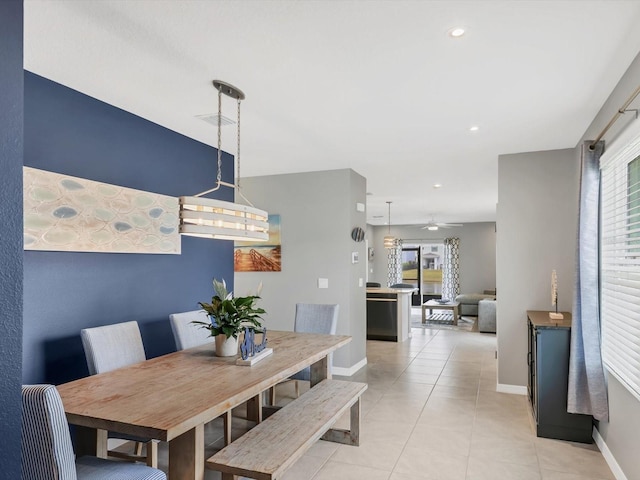 dining space with light tile patterned flooring, ceiling fan with notable chandelier, and plenty of natural light