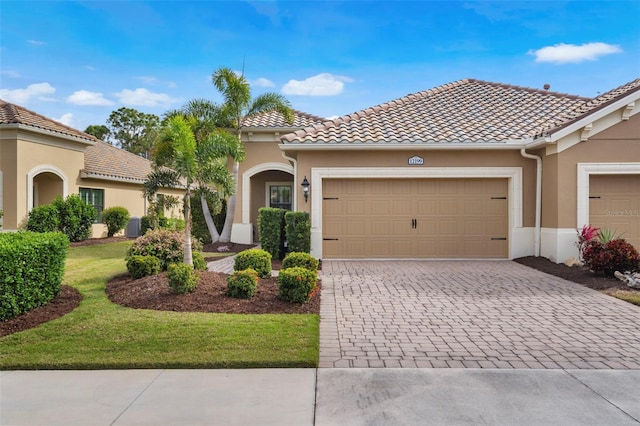 mediterranean / spanish home featuring a garage and a front lawn