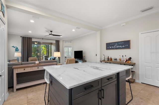 kitchen featuring ceiling fan, ornamental molding, a breakfast bar, and a center island