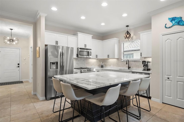 kitchen featuring stainless steel appliances, white cabinetry, decorative light fixtures, and a center island