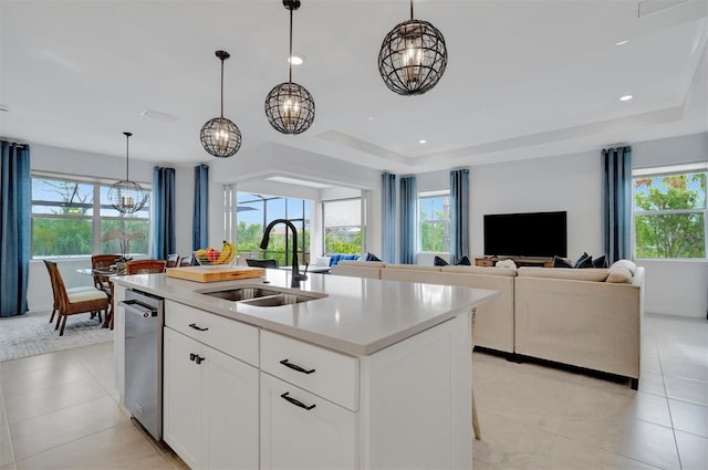 kitchen with pendant lighting, sink, white cabinets, and a center island with sink