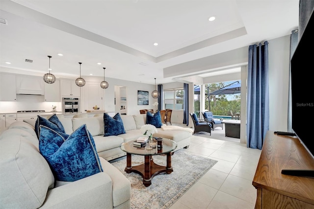 living room with a tray ceiling and light tile patterned floors