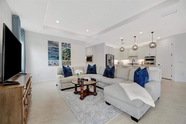 living room with sink, a raised ceiling, and light tile patterned flooring