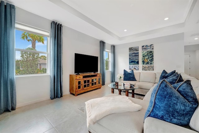 living room with a tray ceiling and light tile patterned floors