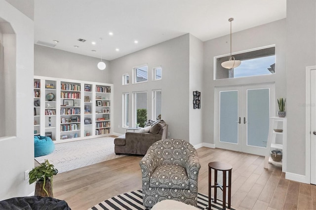 interior space featuring french doors, a towering ceiling, and light hardwood / wood-style floors