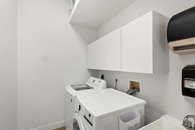 clothes washing area featuring sink, washing machine and clothes dryer, and cabinets