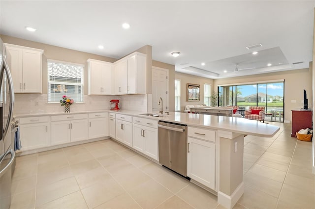 16127 Fortezza Dr, Bradenton, FL 34211 - kitchen featuring dishwasher, a peninsula, a raised ceiling, open floor plan, and tasteful backsplash