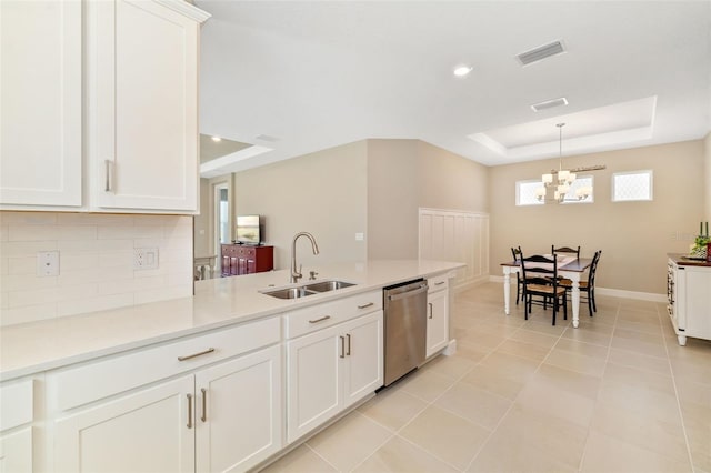 16127 Fortezza Dr, Bradenton, FL 34211 - kitchen with stainless steel dishwasher, a tray ceiling, decorative backsplash, white cabinetry, and a chandelier