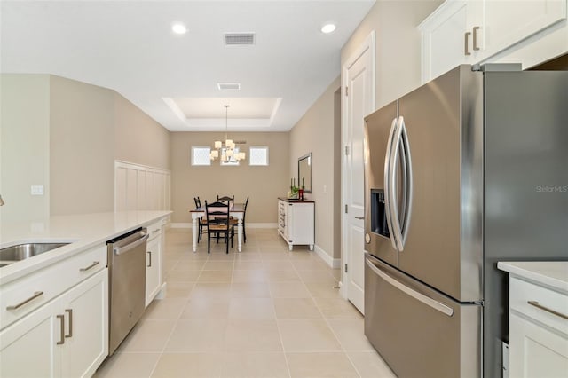 16127 Fortezza Dr, Bradenton, FL 34211 - kitchen featuring stainless steel appliances, a chandelier, a raised ceiling, light countertops, and white cabinetry