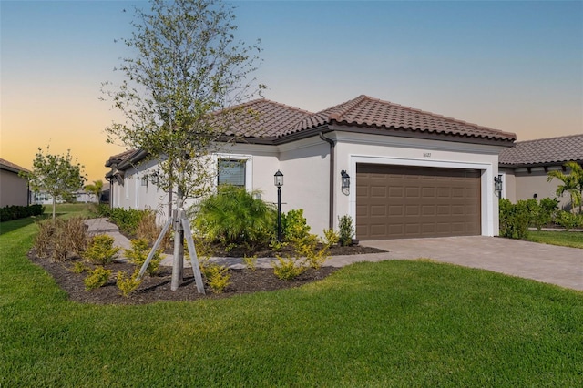 16127 Fortezza Dr, Bradenton, FL 34211 - mediterranean / spanish house featuring an attached garage, a tile roof, a lawn, and stucco siding