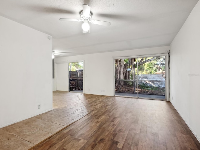 empty room with a textured ceiling, ceiling fan, and light hardwood / wood-style floors