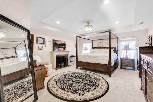 bedroom featuring recessed lighting, a tray ceiling, light colored carpet, and visible vents