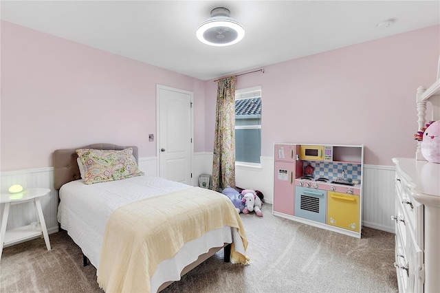 bedroom featuring a wainscoted wall and light colored carpet