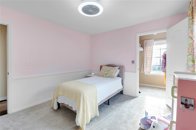 bedroom with light colored carpet and a wainscoted wall