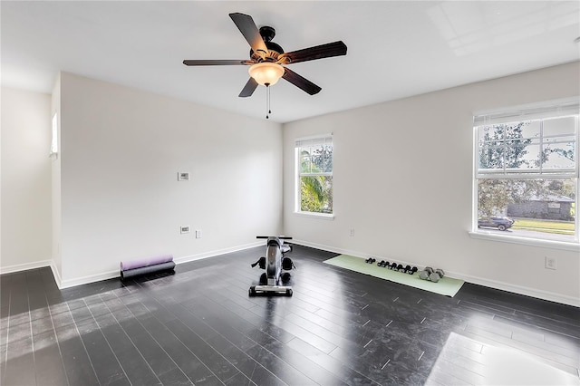 exercise room with baseboards, a ceiling fan, and dark wood-style flooring