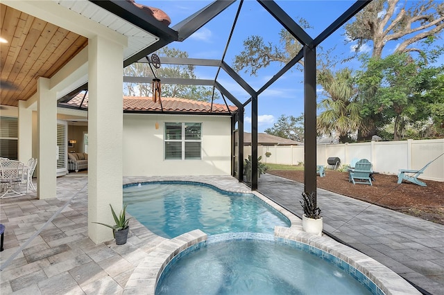 view of pool with a fenced backyard, glass enclosure, a pool with connected hot tub, and a patio