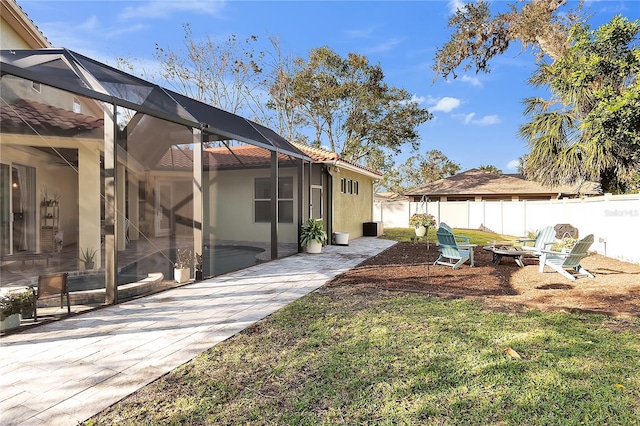 view of yard featuring a lanai, a fire pit, a fenced backyard, and a patio area