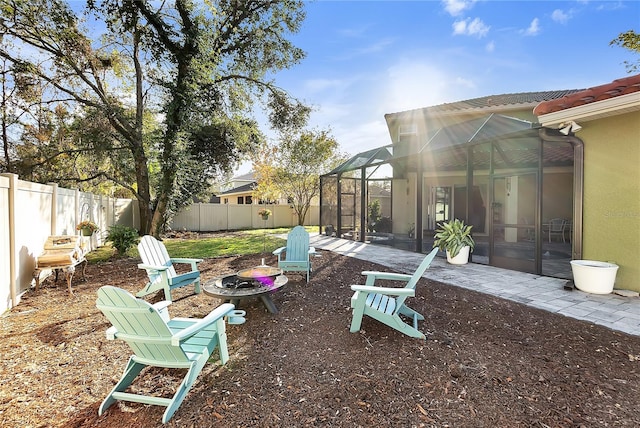 fenced backyard with a fire pit, glass enclosure, and a patio area