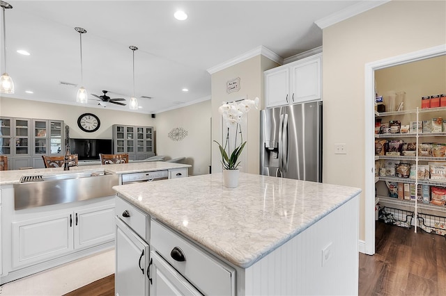 kitchen with stainless steel fridge, a sink, a ceiling fan, a kitchen island, and crown molding