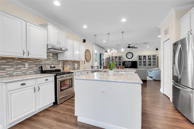 kitchen featuring stainless steel appliances, open floor plan, under cabinet range hood, a center island, and crown molding