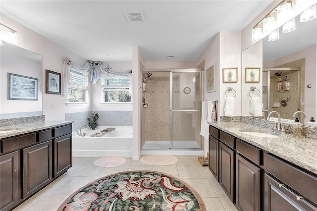 full bathroom featuring a stall shower, tile patterned flooring, a bath, and two vanities