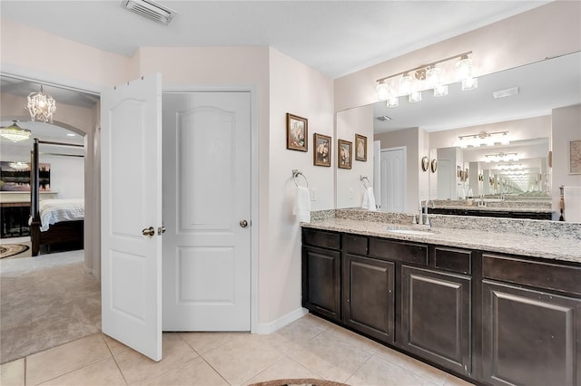 ensuite bathroom featuring tile patterned floors, vanity, and baseboards