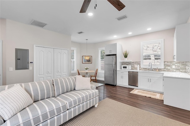 living room with electric panel, dark wood-type flooring, ceiling fan, recessed lighting, and baseboards