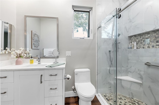 bathroom with a shower stall, toilet, vanity, wood finished floors, and baseboards