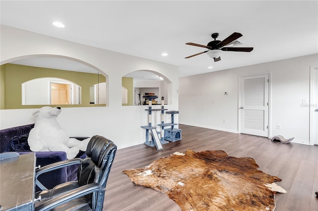 exercise room featuring ceiling fan, wood finished floors, recessed lighting, arched walkways, and baseboards