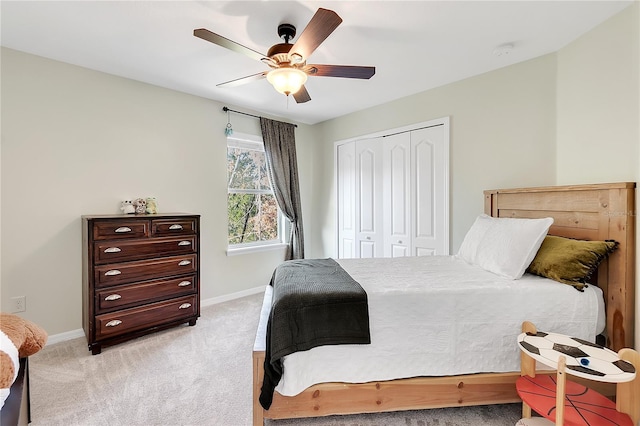 bedroom with baseboards, a closet, light carpet, and ceiling fan