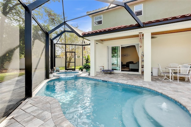 view of pool with a patio, glass enclosure, and a pool with connected hot tub