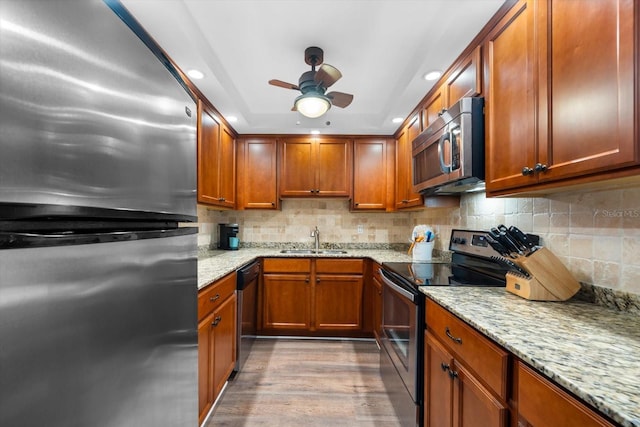 kitchen with light stone counters, sink, appliances with stainless steel finishes, and light wood-type flooring