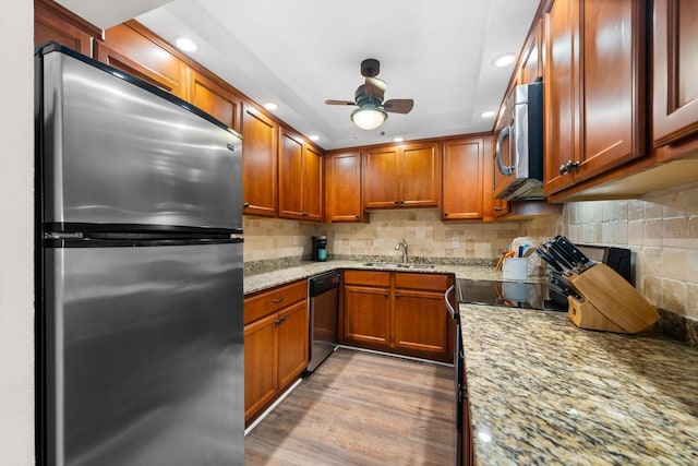 kitchen featuring ceiling fan, sink, light wood-type flooring, appliances with stainless steel finishes, and light stone counters