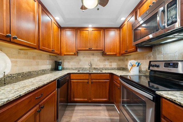 kitchen with appliances with stainless steel finishes, dark wood-type flooring, decorative backsplash, sink, and light stone counters