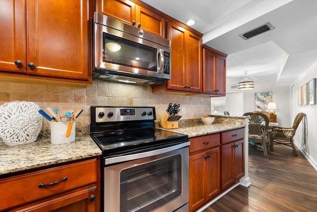 kitchen featuring dark wood-type flooring, appliances with stainless steel finishes, decorative backsplash, and light stone counters