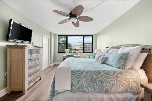 bedroom featuring ceiling fan, a textured ceiling, and light wood-type flooring