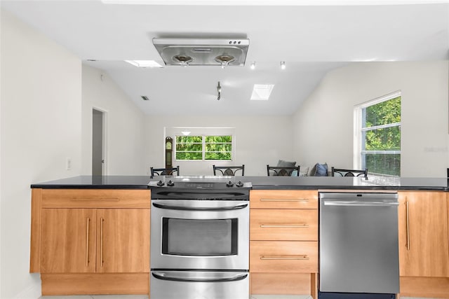 kitchen featuring light tile patterned floors, vaulted ceiling, appliances with stainless steel finishes, and light brown cabinetry