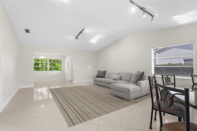 living room with light tile patterned floors, rail lighting, and lofted ceiling with skylight