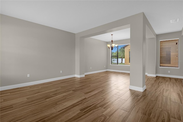 unfurnished living room with an inviting chandelier and hardwood / wood-style flooring