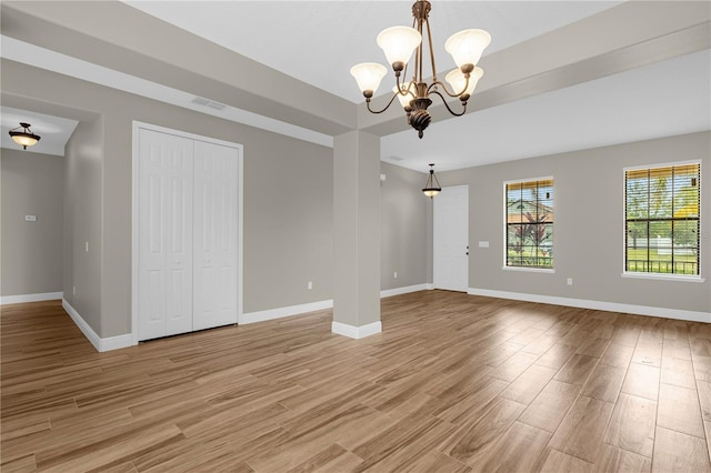 empty room with an inviting chandelier and light hardwood / wood-style floors