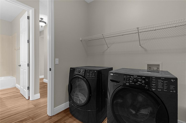 clothes washing area featuring washer and dryer and wood-type flooring